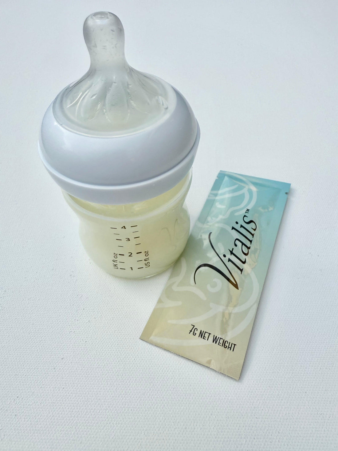Sachet of freeze-dried donor breastmilk next to baby bottle with rehydrated donor breastmilk 
